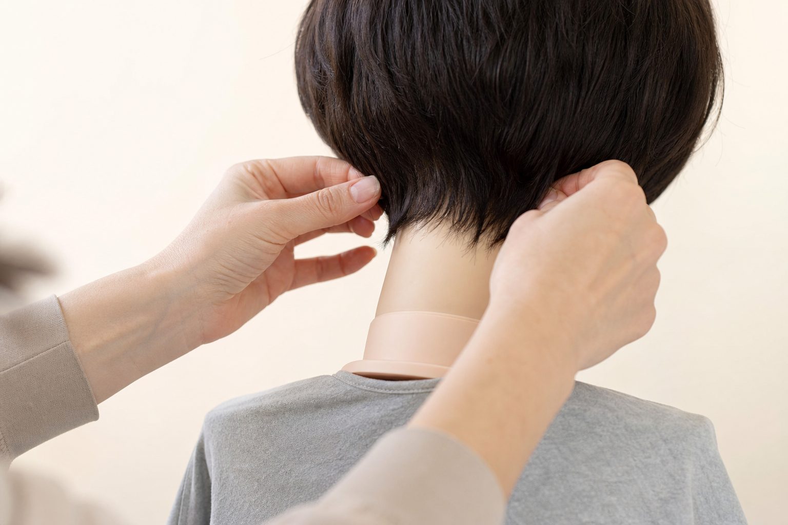 Close view of hands adjusting the nape of a wig on a mannequin head in soft bright studio light