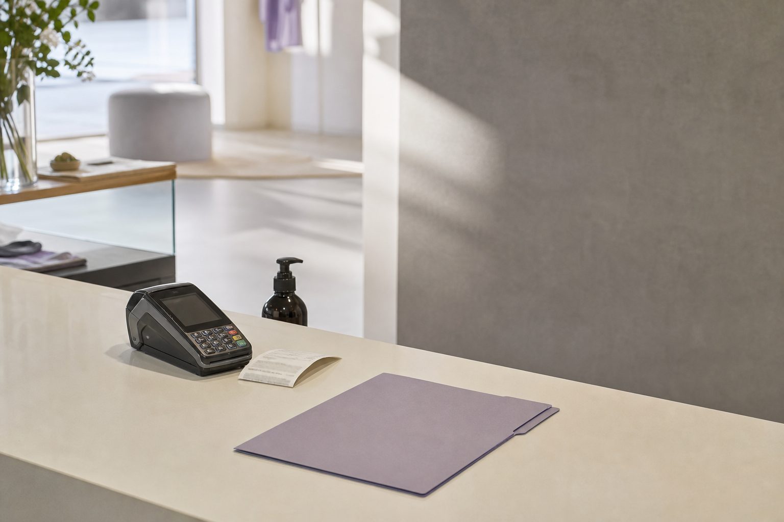 Bright studio checkout counter with a card reader, printed receipt and slim file folder